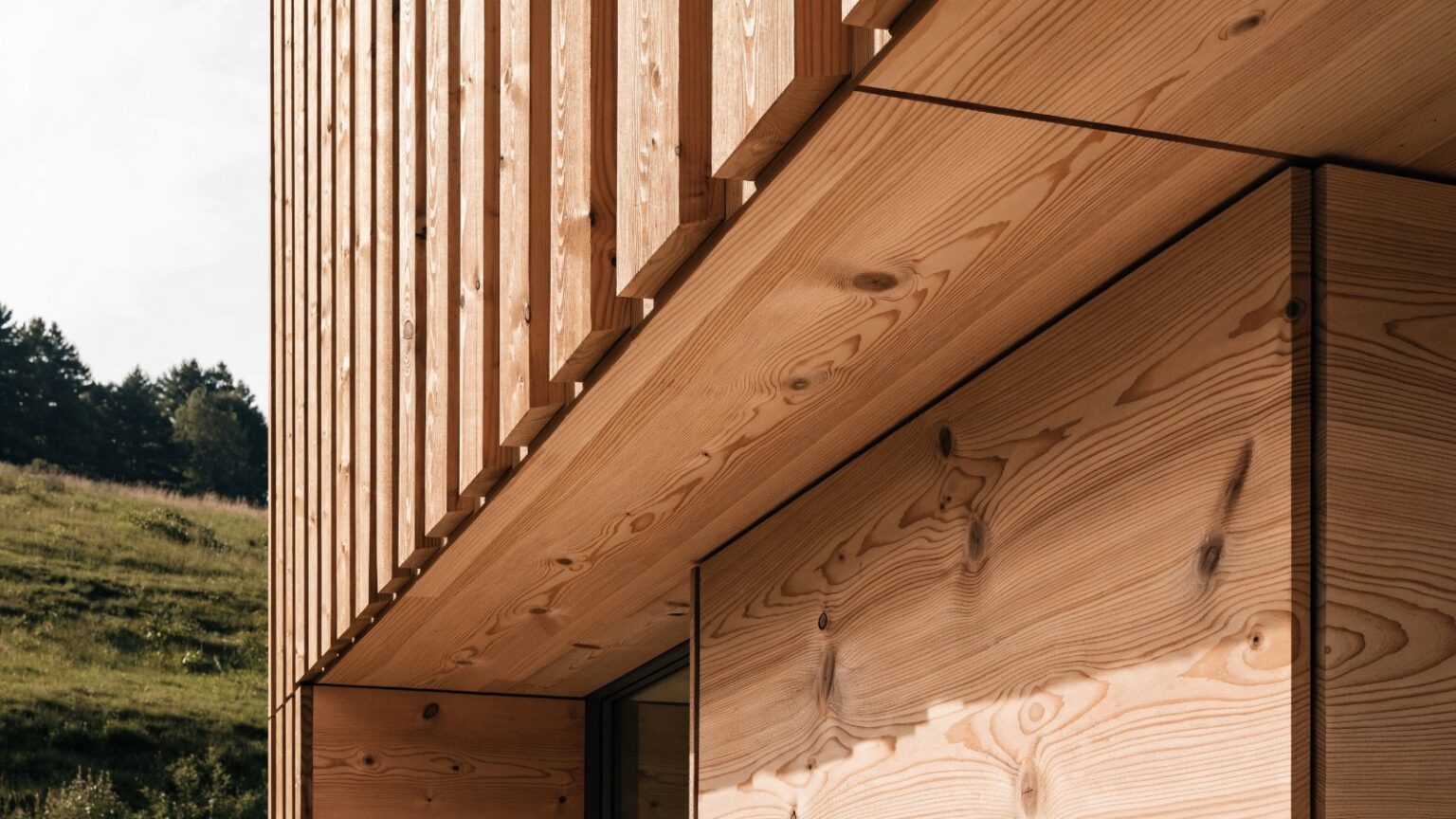 Moderne Holzfassade mit senkrechter Lattung und großformatigen Holzplatten aus natürlichem Lärchenholz an einem Haus im Waldviertel